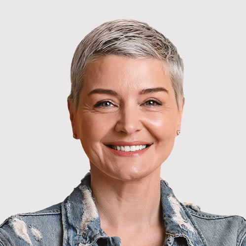 A smiling woman with short, silver hair wearing a denim jacket. She exudes a friendly and approachable demeanor.