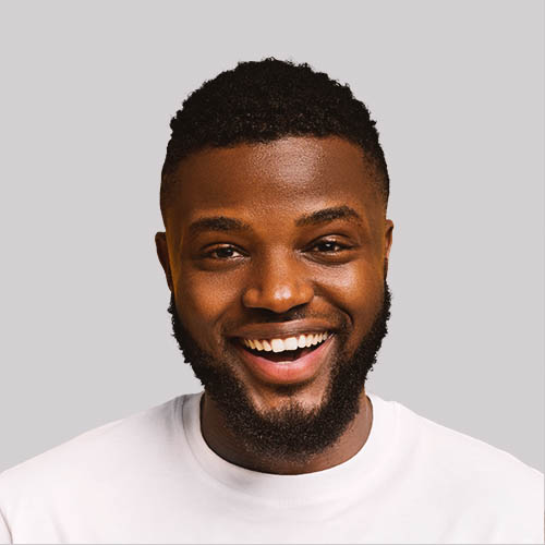 A smiling man with a beard wearing a white shirt against a light gray background. His expression conveys friendliness and approachability.